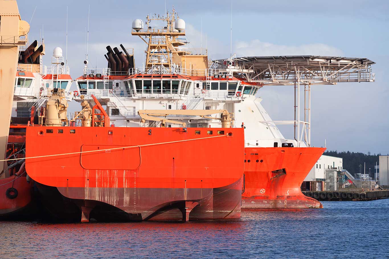 Fleet of offshore vessels moored in Norwegian port at sunny day